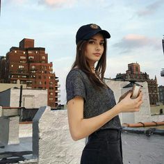 a young woman is holding a hammer and looking at her cell phone while standing on the roof of a building