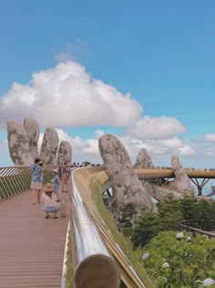 people walking on a wooden walkway with large rocks in the background and one person taking a photo