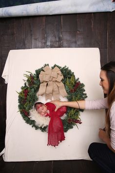 two women are making a christmas wreath on a wall