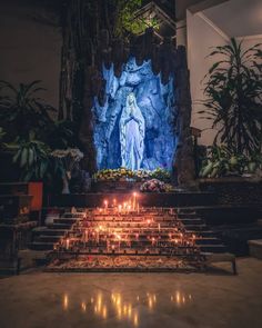 candles are lit in front of the statue