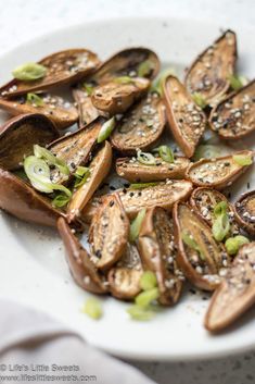 a white plate topped with sliced mushrooms covered in sesame seeds