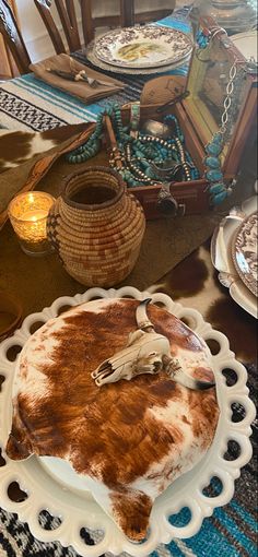 a table topped with plates and bowls filled with food covered in cow hide skin on top of a wooden table