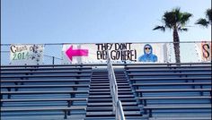 an empty bleacher with signs on it and palm trees in the back ground