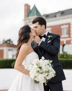 a bride and groom kissing in front of a building