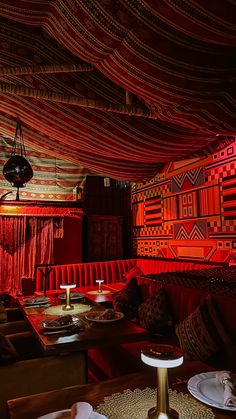 the interior of a restaurant with red lighting and decorative wall coverings on the ceiling