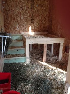 a room that has hay all over the floor and in it is a table with a light on top