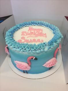 a blue and white cake with pink flamingos on it's side in a box