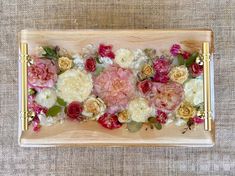 a wooden tray with flowers on it and gold trimming around the edges, sitting on a table