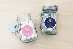 two glass jars filled with white and pink candies on top of a wooden table