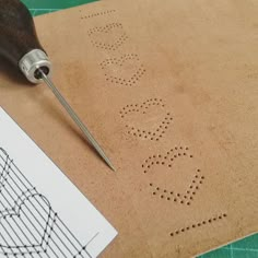 a close up of a piece of paper with holes in it next to a drill