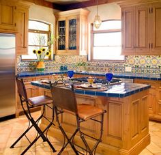 a kitchen with wooden cabinets and blue tile counter tops, two chairs at the island