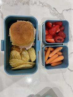 the lunch box is filled with fruit, vegetables and a sandwich on top of it