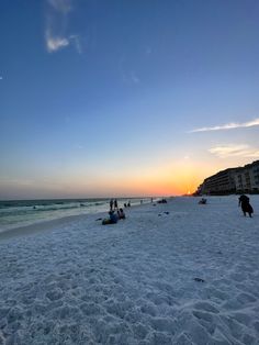 people are on the beach watching the sun go down