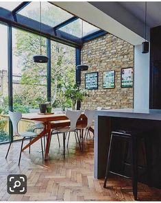 an open kitchen and dining room area with brick walls, wood flooring and large windows