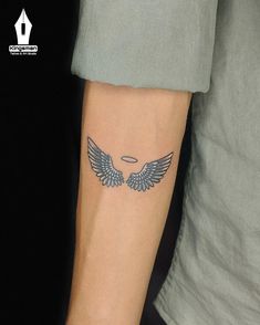 a person with a tattoo on their arm and an angel wings design on the wrist