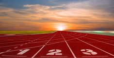 a running track with numbers painted on it at sunset or sunrise in the distance,