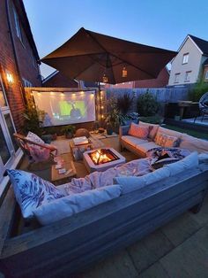 an outdoor living area with couches, tables and umbrellas in the evening time