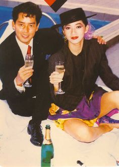 a man and woman sitting next to each other holding wine glasses