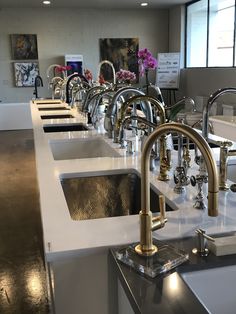 a row of sinks with faucets on them in a room filled with windows