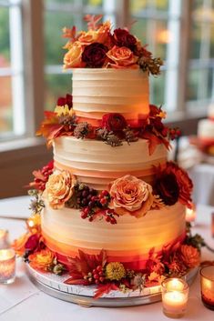 a three tiered wedding cake with flowers and candles on the table next to it