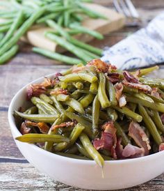 a white bowl filled with green beans and bacon