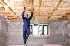 a man is standing on a ladder in a room with exposed ceiling and walls that are being built