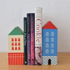 three books are stacked on top of each other in front of a house and bookend