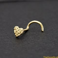 a gold heart shaped nose ring on a black surface