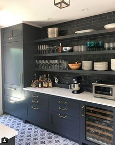 a kitchen filled with lots of counter top space and shelves full of bottles, glasses, and other items