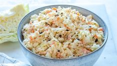 a bowl filled with coleslaw and carrots on top of a white table