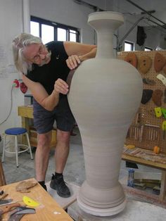 a man is making a vase out of clay