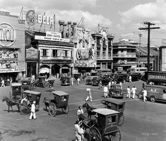 an old black and white photo of people on the street with horse drawn carriages in front of buildings