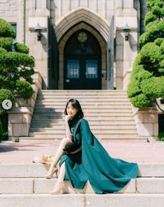 a woman sitting on the steps in front of a building with stairs and trees around her