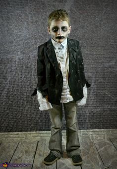 a young boy dressed up in a costume and makeup is standing on a wooden floor