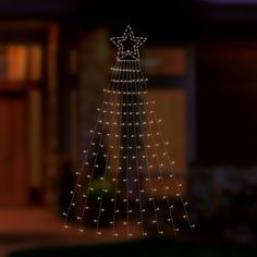 a lighted christmas tree in front of a house