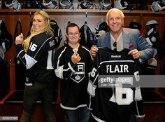 two men and a woman holding up hockey jerseys