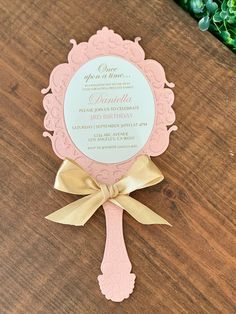 a pink and gold wedding card on top of a wooden table