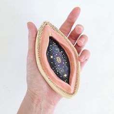 a hand is holding an object made out of clay and painted with gold speckles