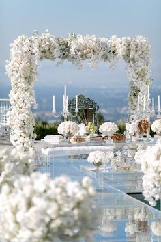 an outdoor wedding setup with white flowers and candles on the side of the ceremony aisle