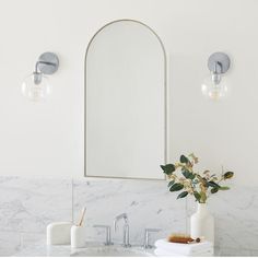 a bathroom with marble counter tops and white walls, along with an oval mirror above the sink