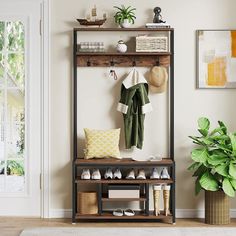 a coat rack with shoes and hats on it in front of a door, next to a potted plant