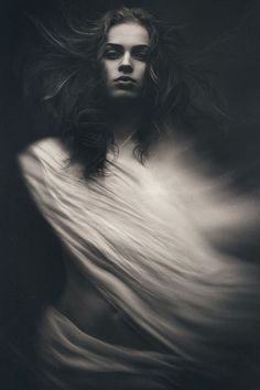 a black and white photo of a woman with her hair blowing in the wind,