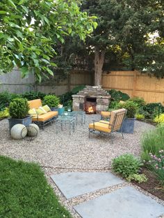 an outdoor patio with seating and fire pit in the middle, surrounded by greenery