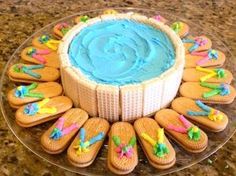 a cake decorated with flip flops and blue frosting on a glass platter