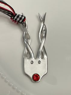 a pair of scissors with red crystal eyes on the end of each one, attached to a string