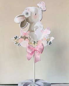 a cake topper that is shaped like a bunny with pink bows and flowers on it