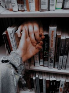 a person reaching for books on a book shelf