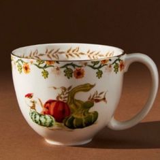 a coffee cup is sitting on a table with flowers and leaves painted on the side