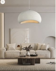 a living room with a couch, coffee table and lamp hanging from the ceiling above it