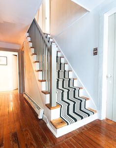 a stair case with black and white carpet on the bottom, next to a wooden floor